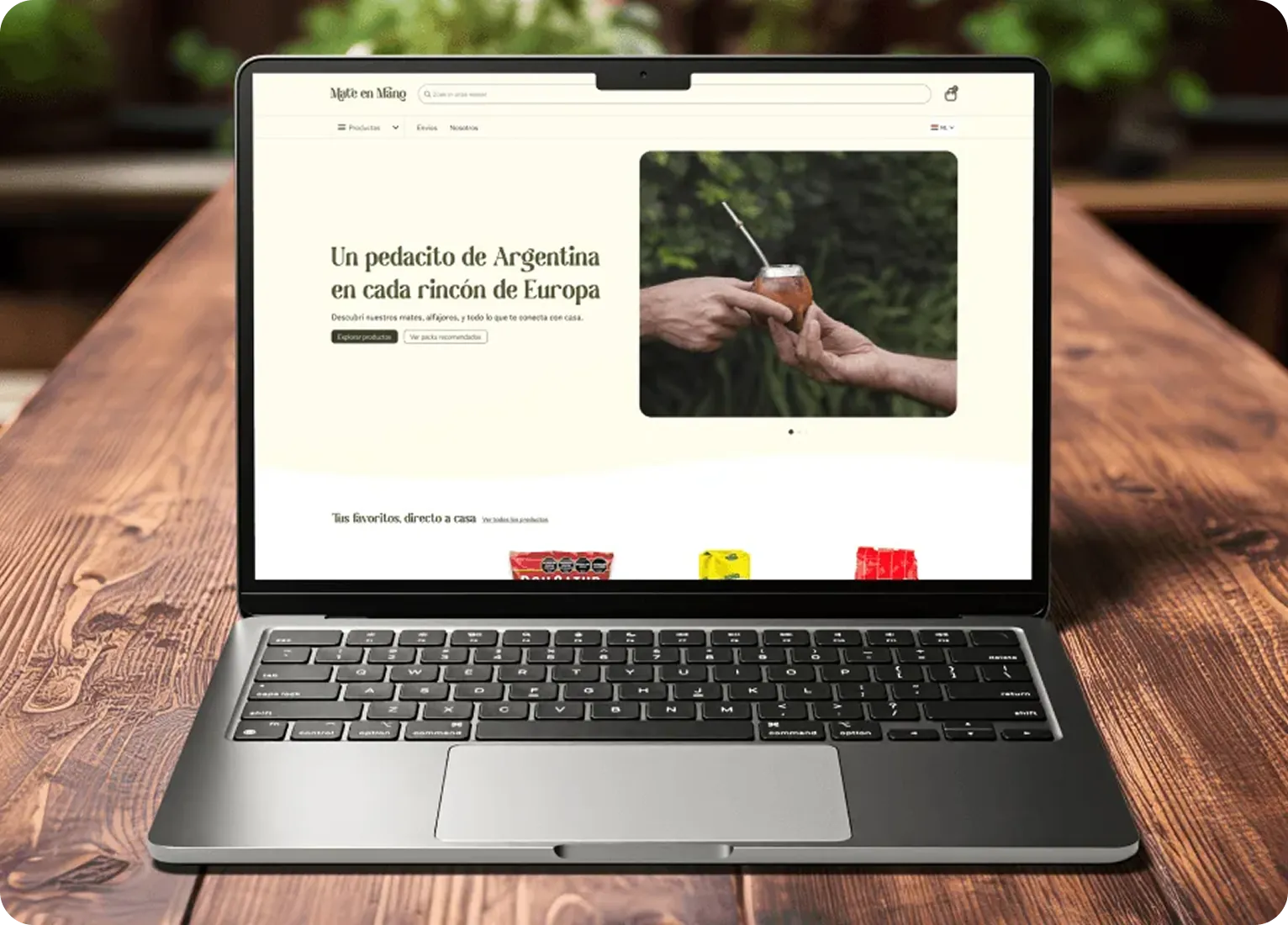 The Mate en Mano homepage open on a laptop, on a wooden table